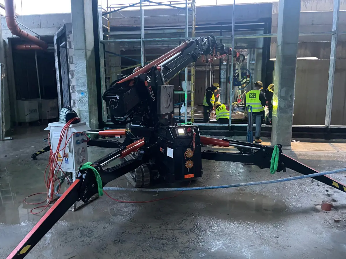 Elektryczny mini żuraw JK Lift wspiera ekipę monterów przy szkleniu wewnątrz hali w Koszalinie