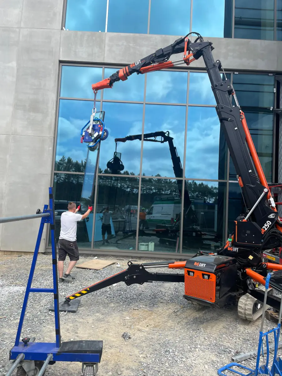 Mini żuraw BG Lift M250 montuje taflę szkła w przeszklonej elewacji budynku biurowego w Niemczech