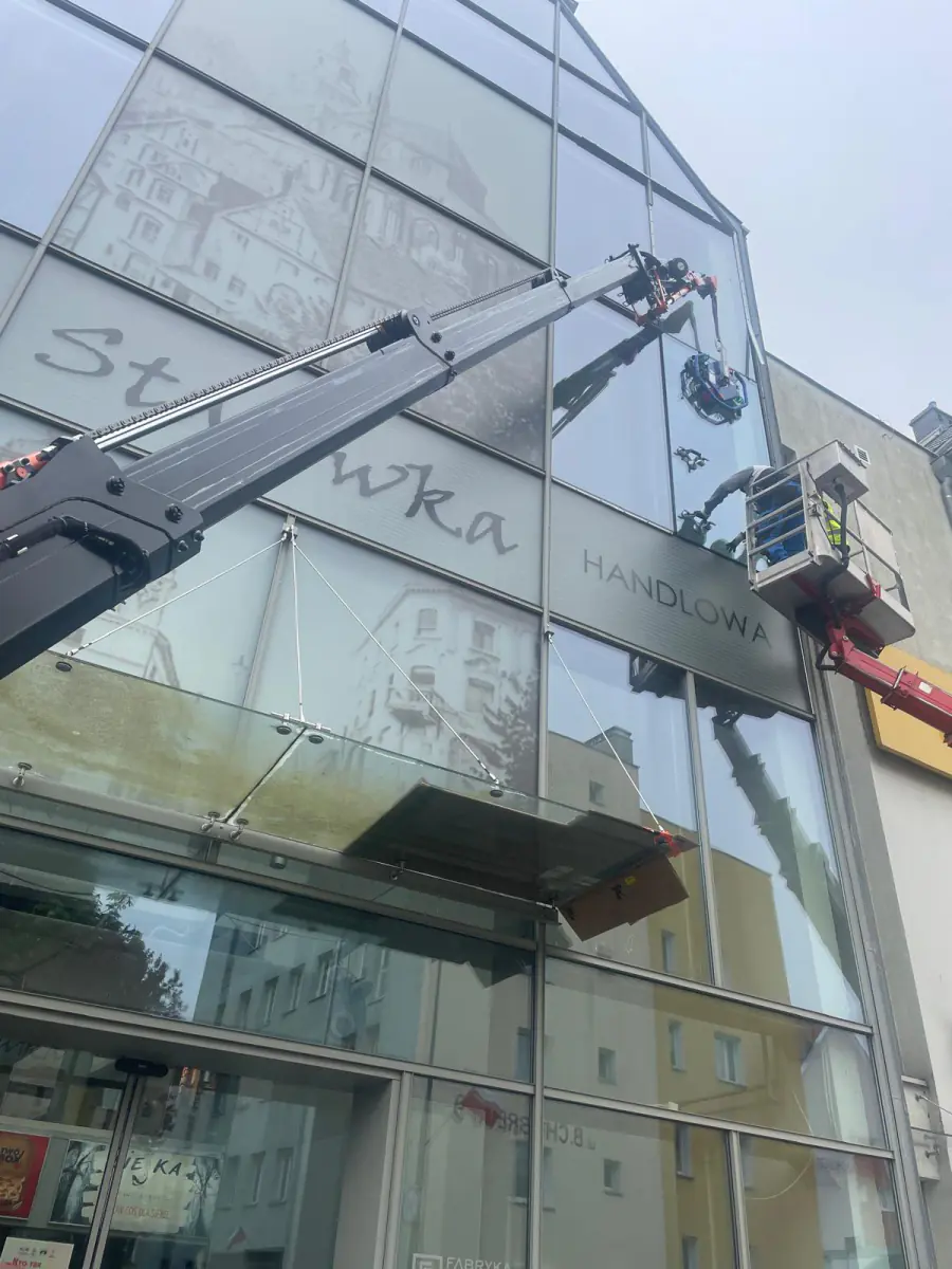 Mini żuraw JK Lift wymienia taflę szkła w przeszklonej elewacji galerii handlowej Starówka w Stargardzie