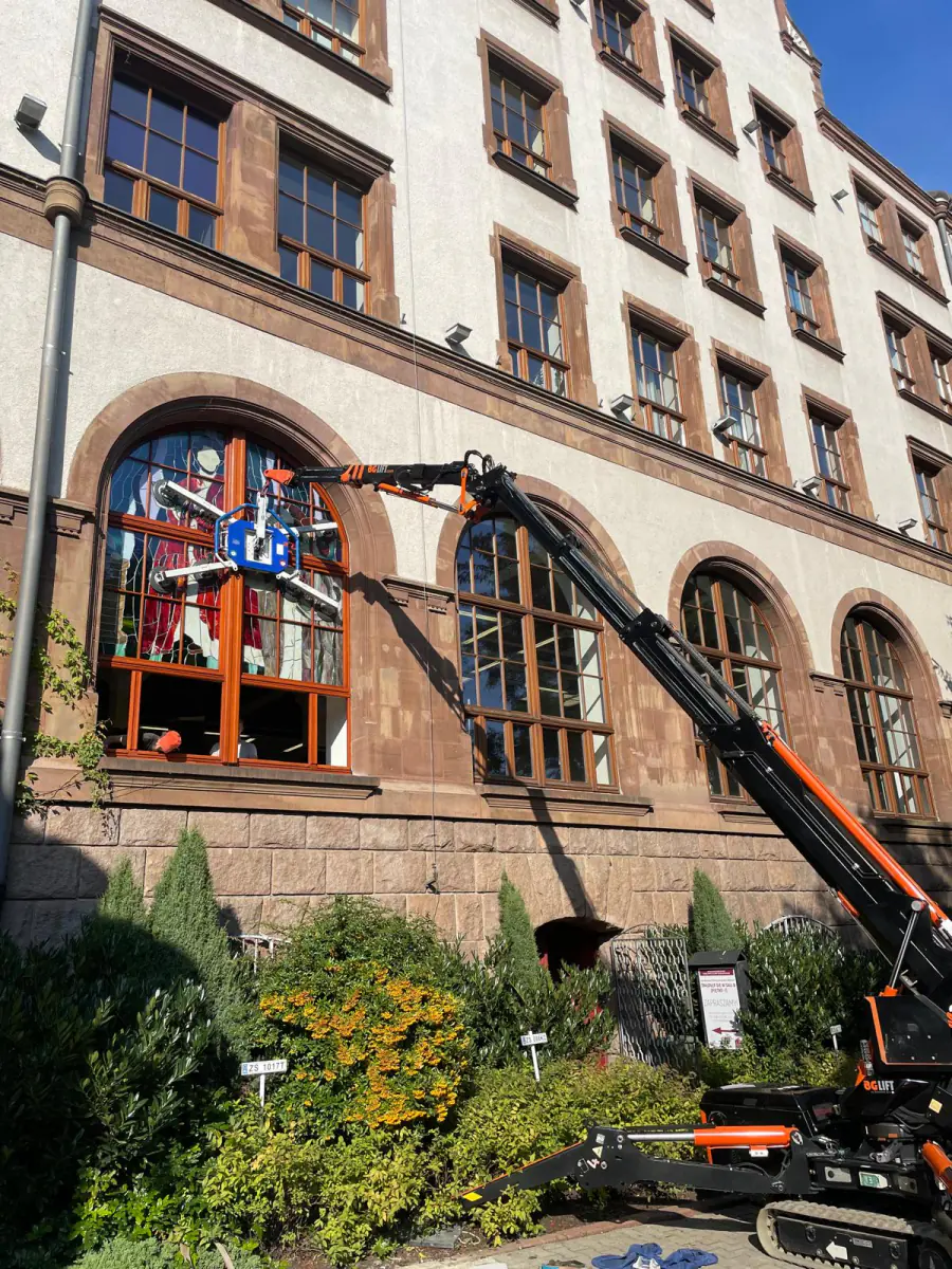 Wysięgnik mini żurawia JK Lift sięga do łukowego okna zabytkowej szkoły salezjańskiej w Szczecinie