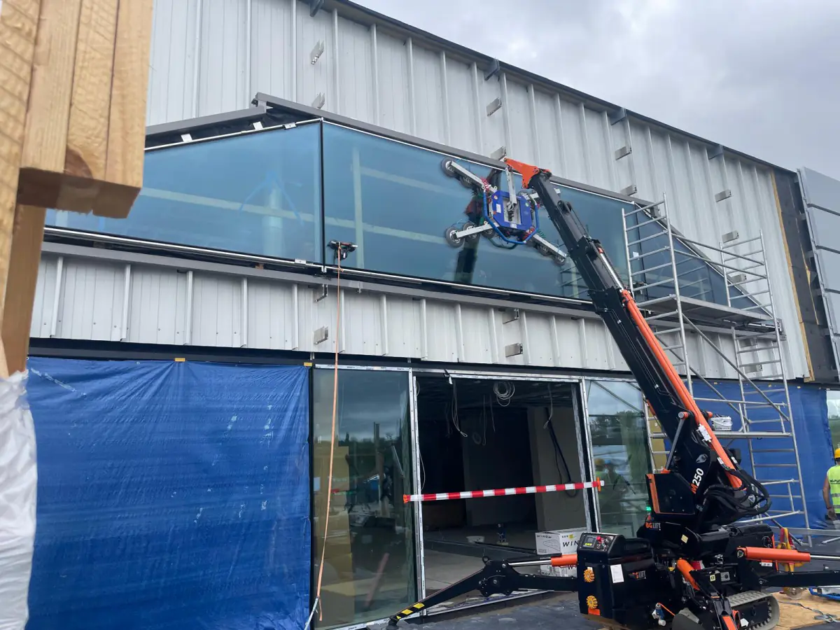 Mini żuraw JK Lift montuje przeszklenie górnej kondygnacji salonu samochodowego Porsche w Szczecinie